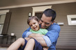 © Monkey Business - Father Hugging Son As They Sit On Porch Of House Together