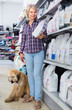 © caftor - female with Afghan Shepherd puppy choose pet food in zoo store