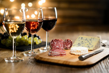 Three Glass Of Red Wine, Rose Wine And White Wine With French Cheese And Delicatessen In Restaurant Wooden Table With Romantic Dim Light And Cosy Atmosphere