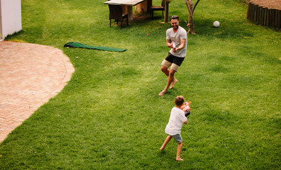 Wall Mural - Father and son having fun with water guns outdoors