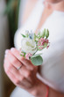 Bride with tender arms holds green boutonniere