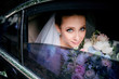 Bride with blue eyes holds tender wedding bouquet sitting in the car