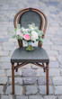 Bouquet of white and pink flowers stands on grey chair on the streets