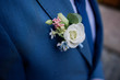 White boutonniere pinned to groom's blue jacket