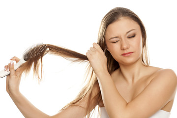 young girl has a problem with combing hair on white background