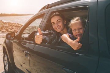 Happy family on a road trip in their car. Dad, mom and daughter are traveling by the sea or the ocean or the river. Summer ride by automobile