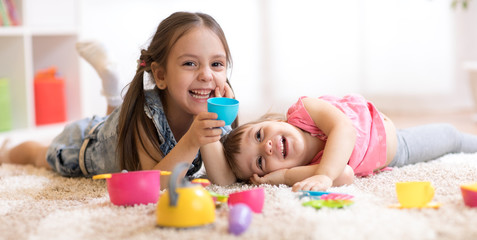 Cute funny children playing with dishware toys at home