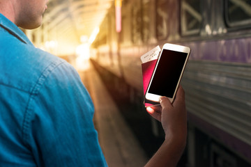 Man holding passport and smart phone with blank waiting in a train station