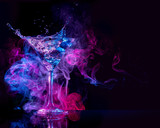 cocktail splashing and multicolored smoke in a black background