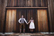 Portrait Of Smiling Young Couple Standing Against Wooden Barn