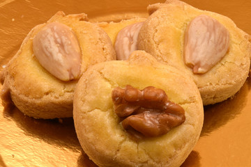 Cookies or biscuits with walnut and almond on golden background.