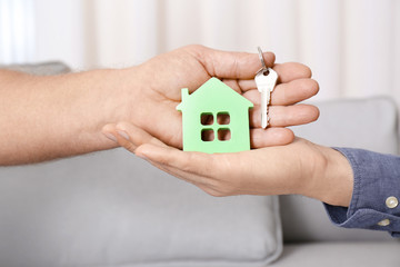 Real estate agent with senior man holding house model and key indoors