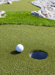 Golf ball next to the cup on a sunny day.