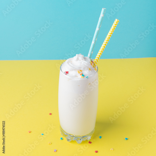 Plakat Napój mleczny w przezroczystym szkle, koktajl na żółto-niebieskim tle. Zdrowe odżywianie