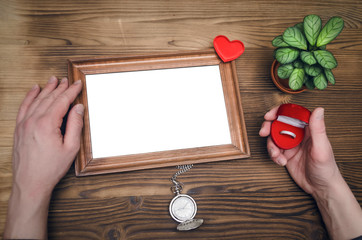 Wall Mural - Photo frame with copy space in male hands and wedding ring in a present box. Declaration of love. Offer to get married. Miss of girl friend.