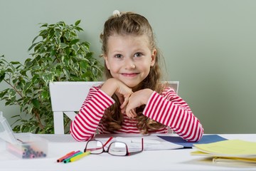 Cute junior schoolgirl with blond hair, smiling, drawing in a sc