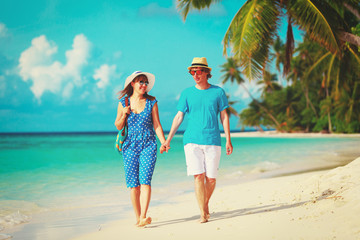 happy loving couple walking on tropical beach