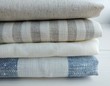 Pile of striped white grey blue red linen cotton fabrics on white background. Different colours. Food photo props. Natural linen cotton fabric. 