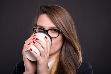 Young confident business woman drinking coffee to go