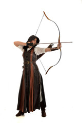 full length portrait of girl wearing brown  fantasy costume, holding a bow and arrow, on white studio background. 