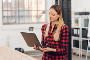 Wall Mural - Attractive blond woman using a handheld laptop