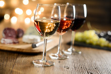 Three Glass Of Red Wine, Rose Wine And White Wine With French Cheese And Delicatessen In Restaurant Wooden Table With Romantic Dim Light And Cosy Atmosphere