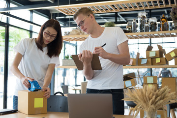 startup small business owner working with computer at workplace. freelance man & woman seller check product order, packing goods for delivery.  Online selling, e-commerce, shipping concept