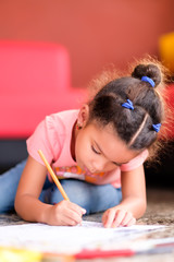 Cute multiracial small girl drawing on a coloring book