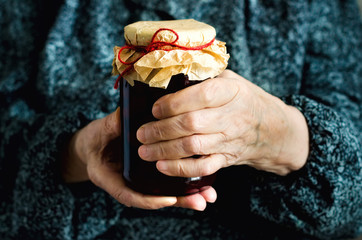 Senior woman holding jar of homemade cherry jam. Banner. Copy space.