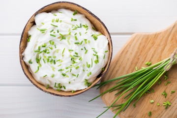 Bowl of cream cheese with green onions, dip sauce on wooden table.