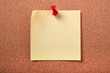 One single yellow square sticky post it note pinned with pushpin to a cork notice or bulletin board background photo