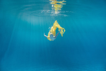 Sticker - underwater picture of beautiful young woman in dress swimming in swimming pool