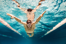 Underwater Picture Of Young Swimmer In Cap And Goggles Training In Swimming Pool
