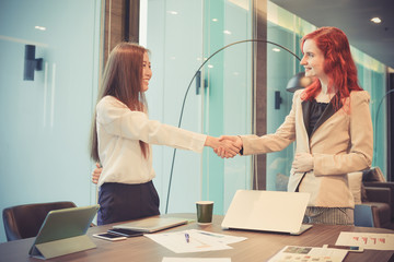 Western business women shaking hands in a meeting room, Multi ethnic