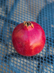 Whole red pomegranate on a table on a terrace