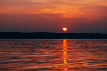 Wall Mural - red sun at sunset with orange sky over sea