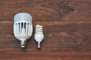 Energy saving light bulbs on wooden background, top view.