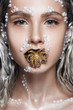 Beautiful woman portrait with art make up, pearl beads on face and gold octopus in mouth.