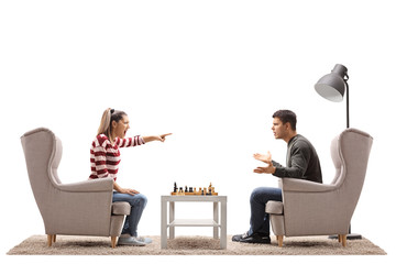 Poster - Young couple seated in armchairs playing chess and arguing