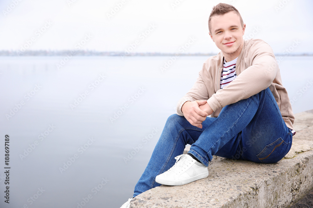 Hipster teenager sitting near river