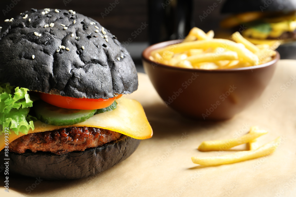 Tasty black burger on table