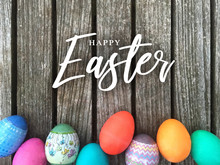 Happy Easter Calligraphy Text Message With Colorful Decorated Eggs Over Rustic Wooden Background
