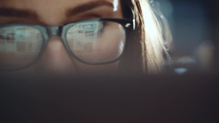 Closeup of attractive young woman looking at monitor while working at modern office and using laptop, hipster girl wearing glasses using computer touchscreen, closeup eyes