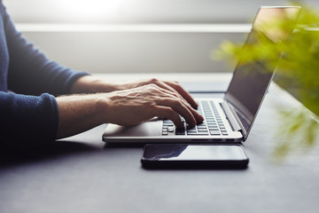 Man in office behind table working on laptop