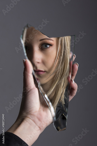 Fotomural Woman looking at her face in shard of broken mirror