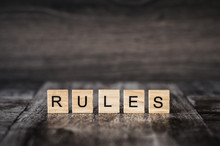 The Word Rules Made Of Bright Wood Cubes With Black Letters On A Dark Wooden Background