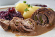 beef roulade with red cabbage, potatoes and sauce, german meat roll stuffed with cucumbers and bacon,  close up