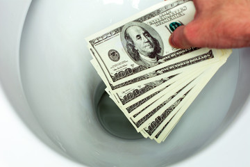 Flush money down the toilet, throws dollar bills in the toilet, loss concept, close up, selective focus