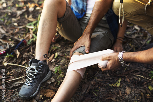 Fotografía Man putting bandage on his partner's knee in the jungle