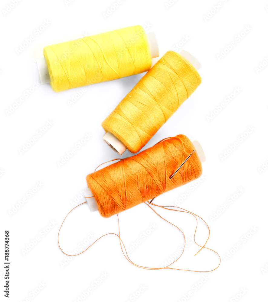 Spools of sewing threads and needle on white background